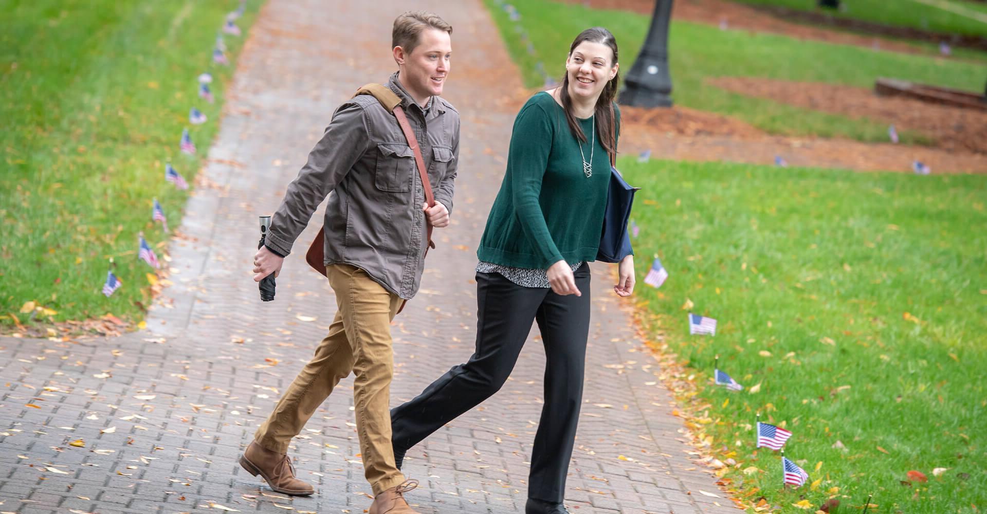 a woman and a man walking on campus